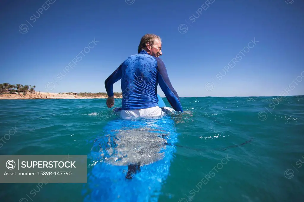 Caucasian man floating on surfboard
