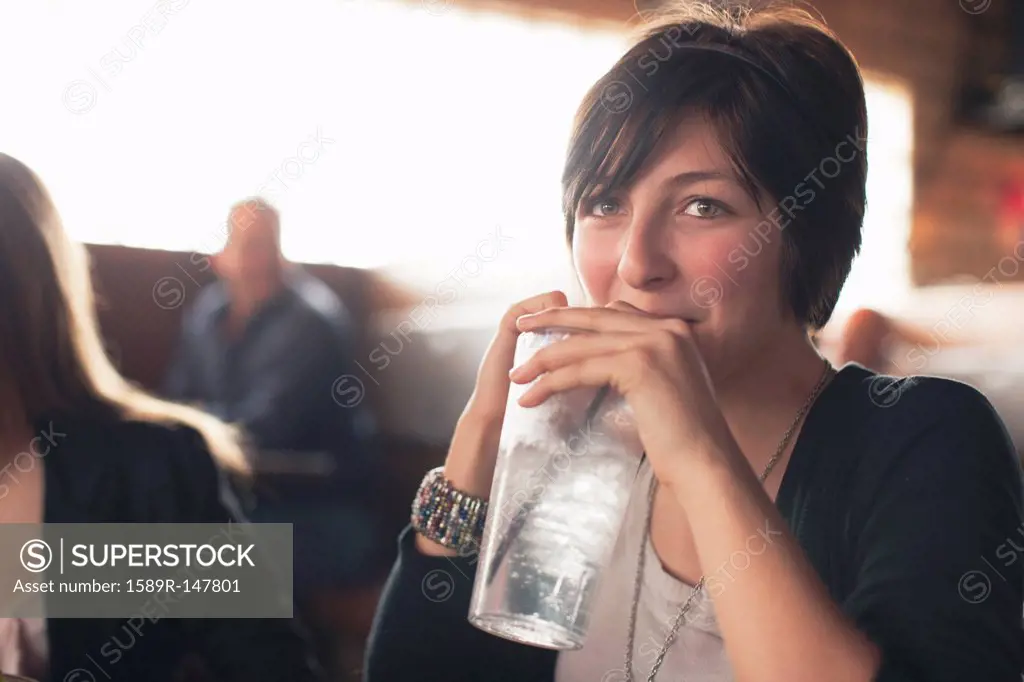 Caucasian teenager drinking water in restaurant