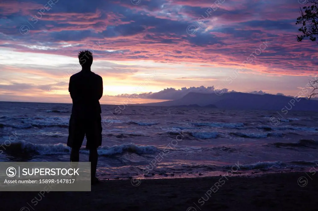 Caucasian man standing on beach viewing sunset