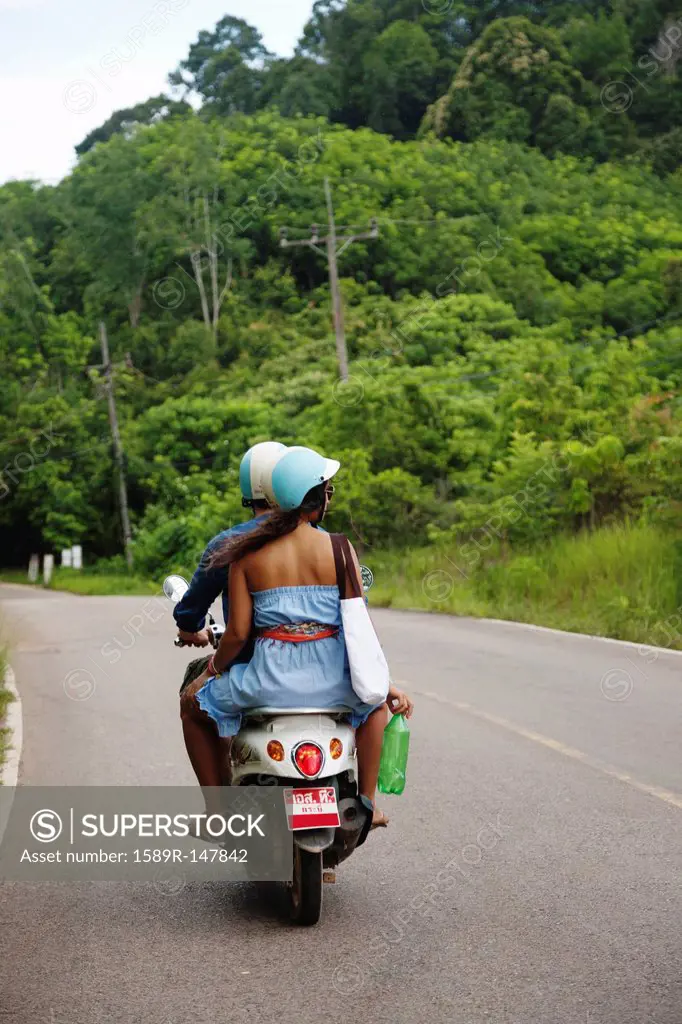Couple riding scooter in remote area