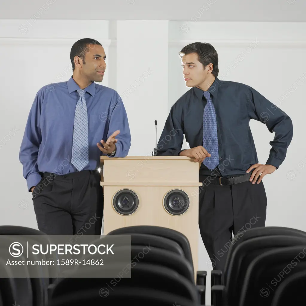 Two businessmen leaning on podium