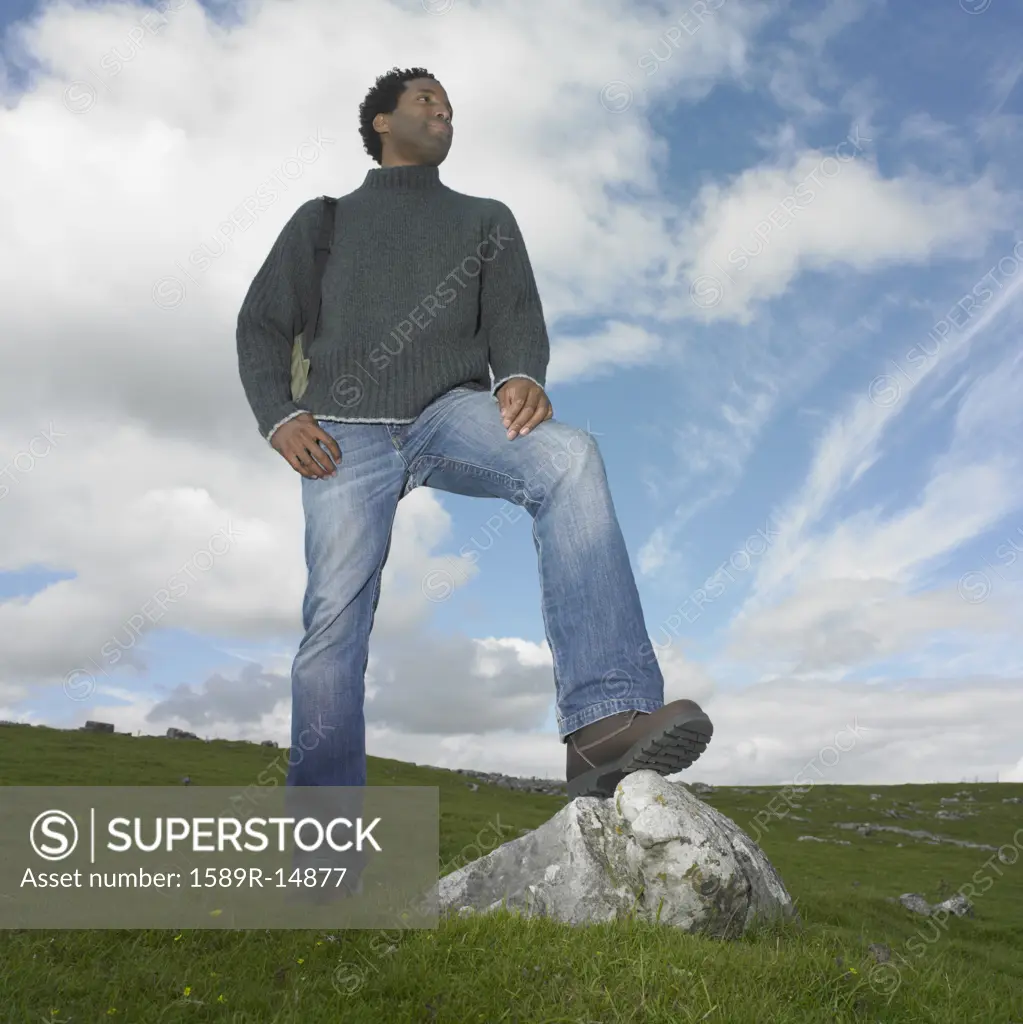Man standing with one foot on a rock