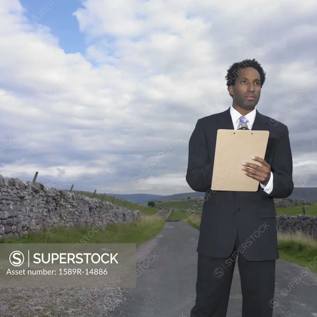 Businessman writing on a clipboard in rural location