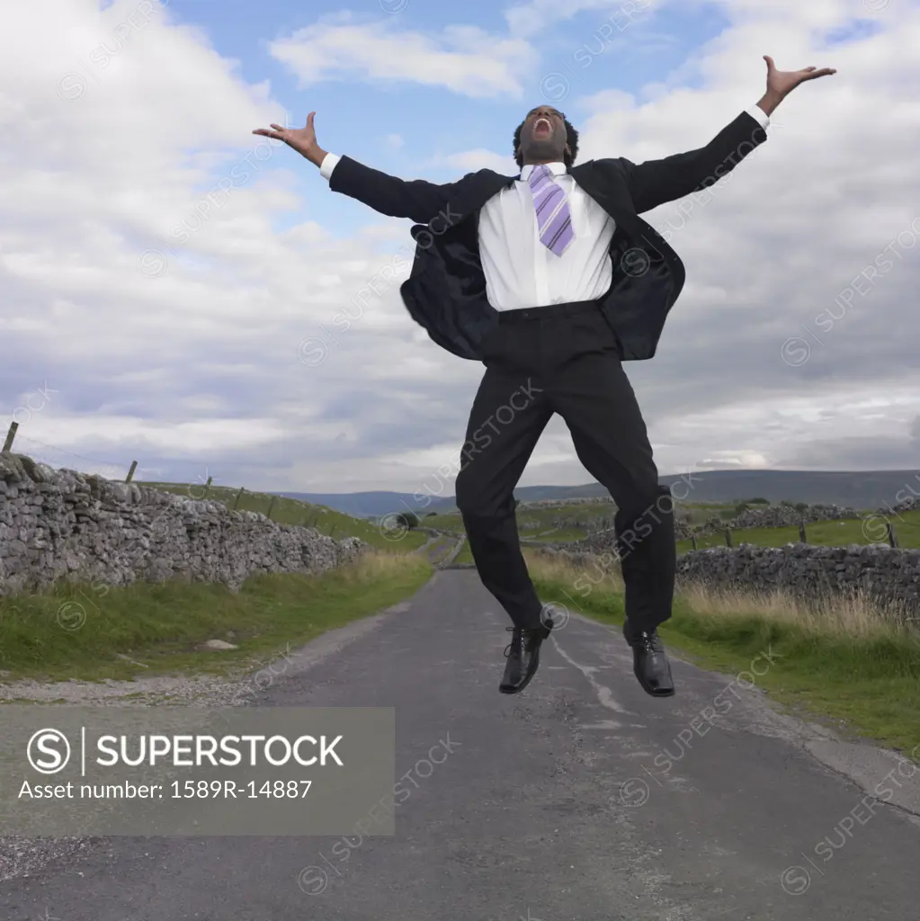 Businessman jumping for joy in rural location
