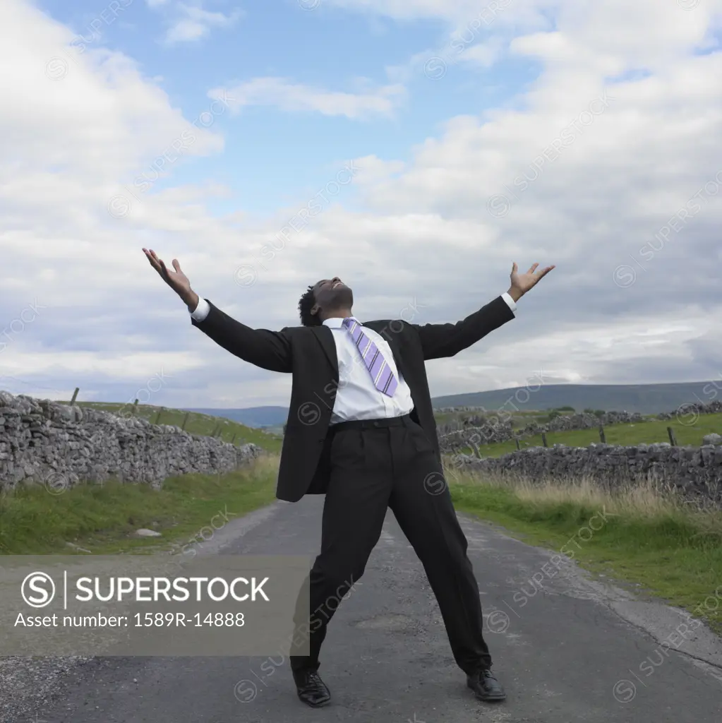 Businessman with his arms outstretched in rural location