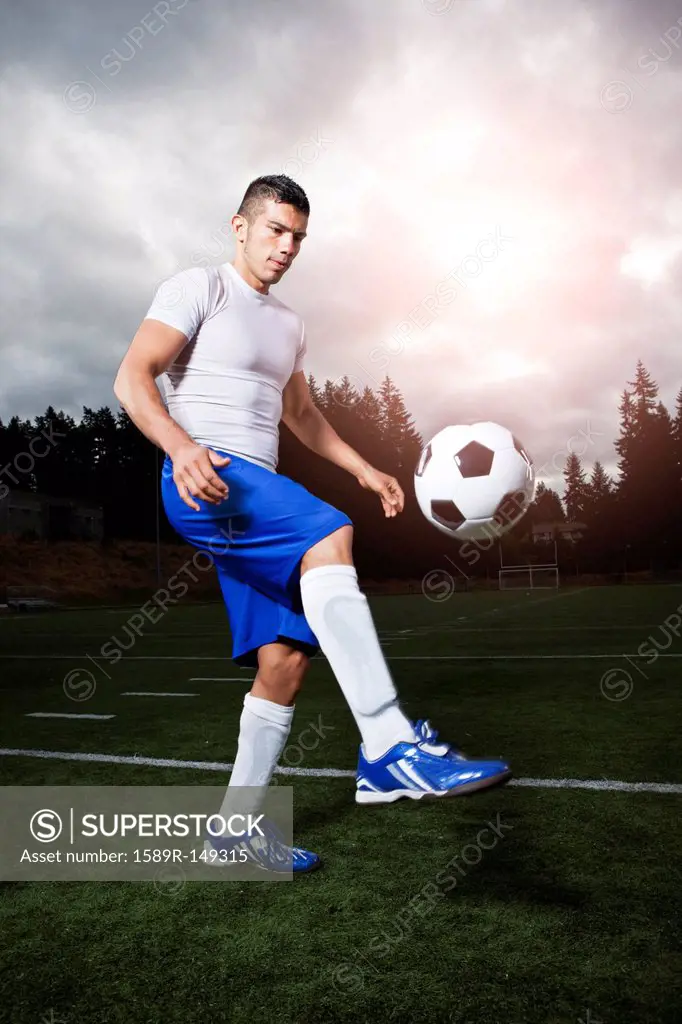 Hispanic athlete kicking soccer ball