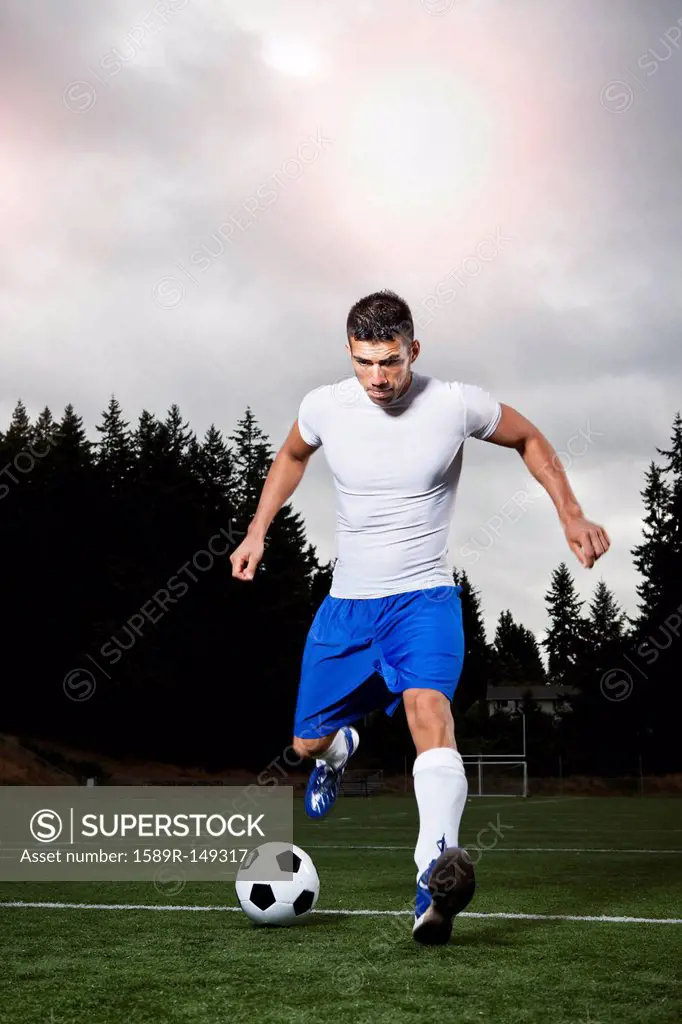 Hispanic athlete kicking soccer ball
