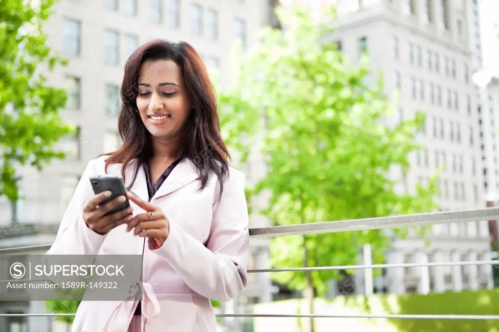 Indian businesswoman text messaging on cell phone
