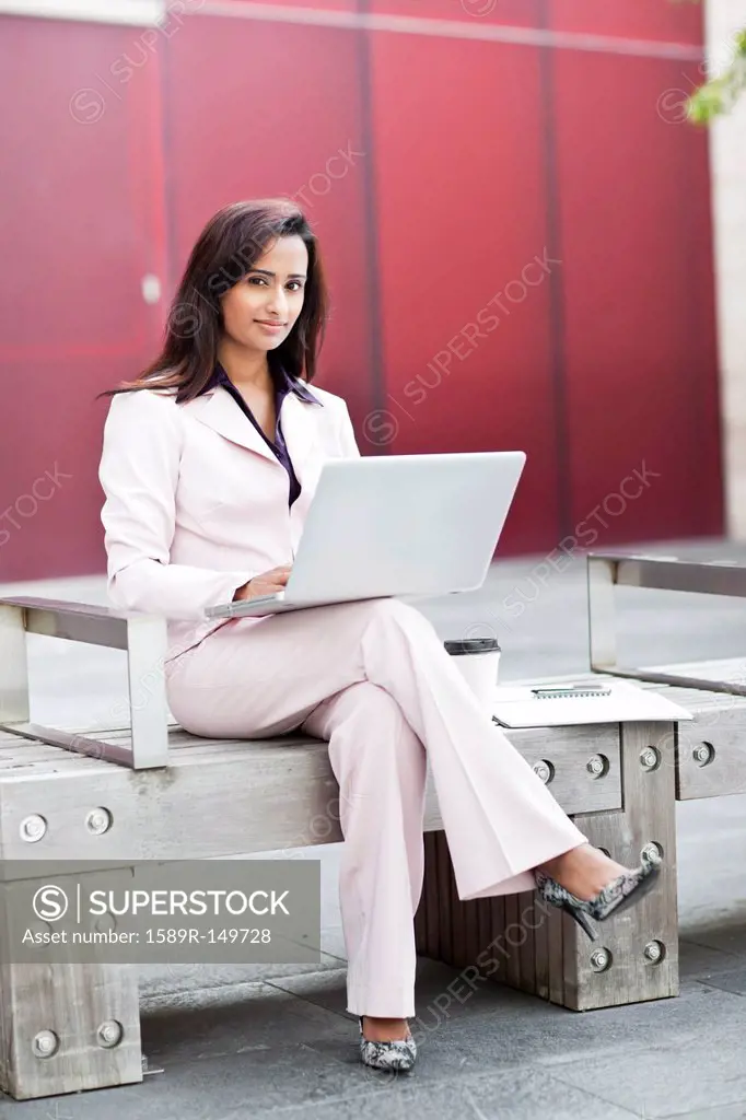 Indian businesswoman using laptop on bench