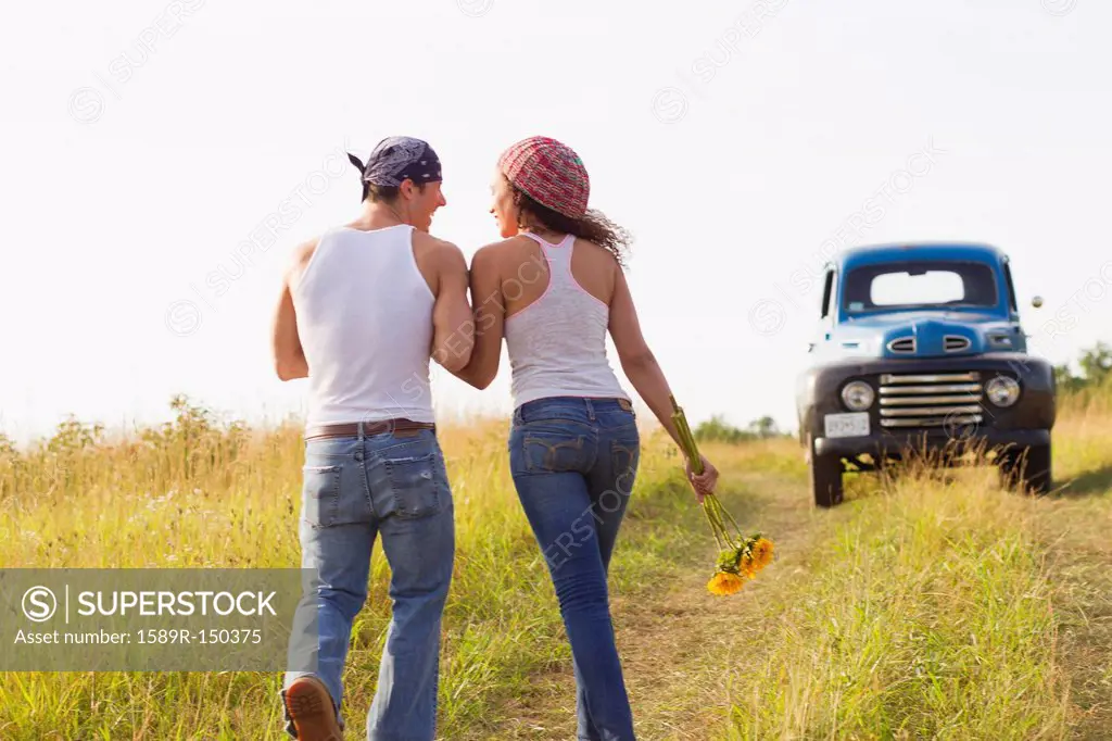 Couple walking in field near truck