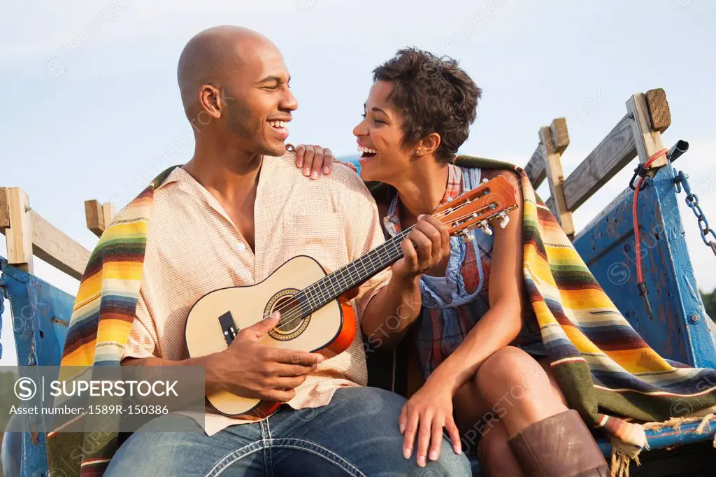 Man playing ukulele for wife on back of truck
