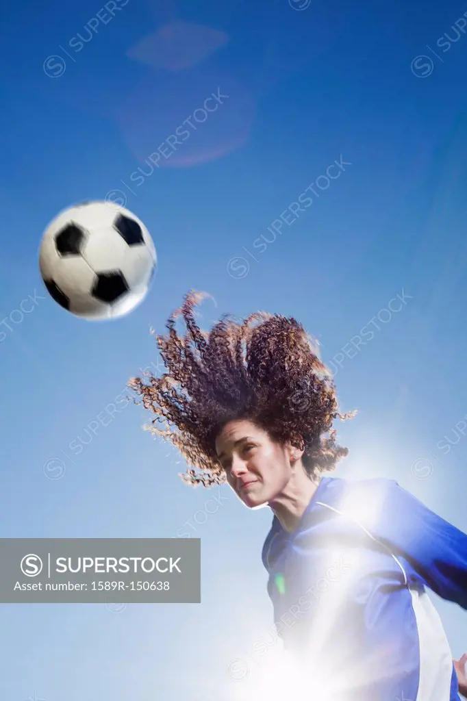 Caucasian woman heading soccer ball