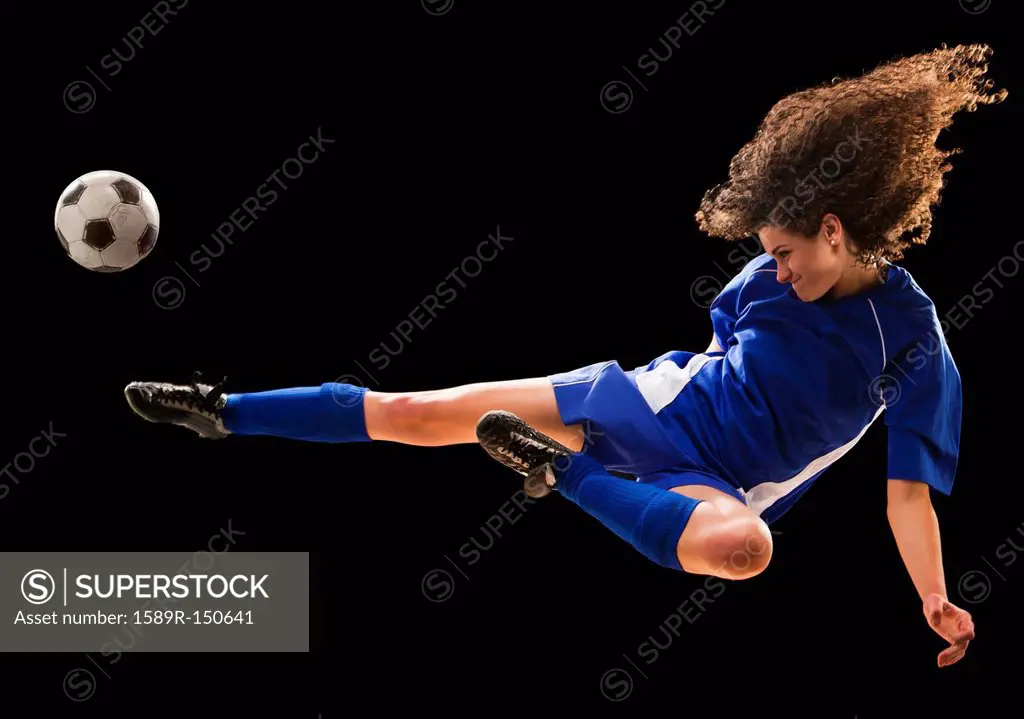 Caucasian soccer player kicking ball in mid_air