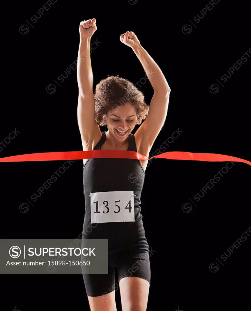 Caucasian woman running across race finish line