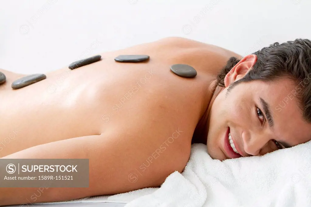 Hispanic man having hot stone therapy