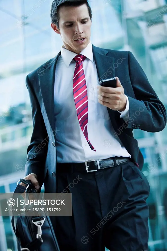 Caucasian businessman looking at cell phone outdoors
