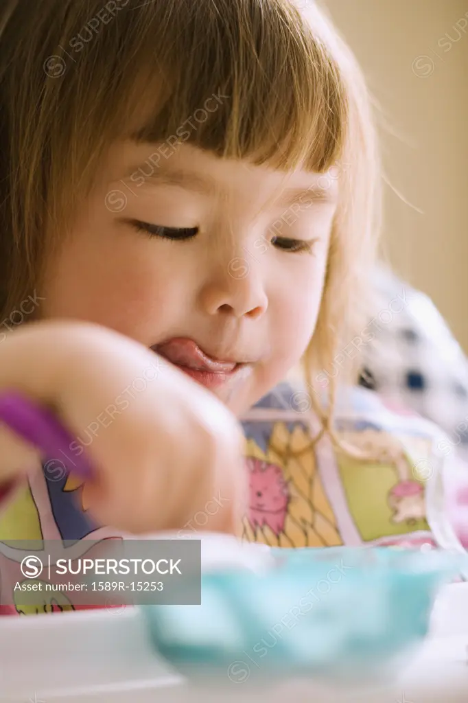 Close up of young girl eating in high chair