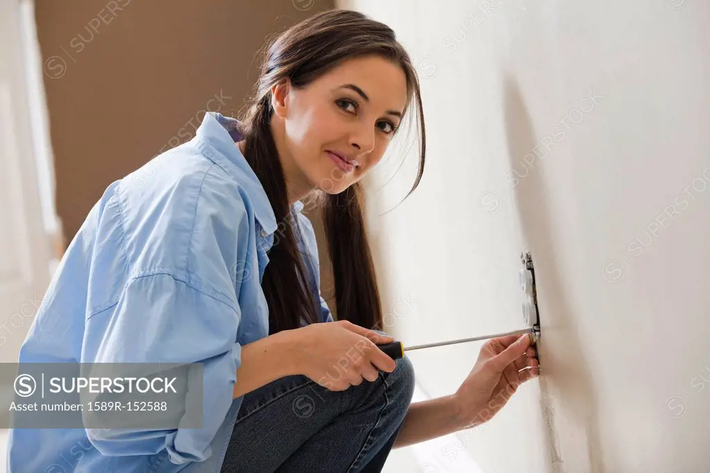 Caucasian woman working on electrical outlet