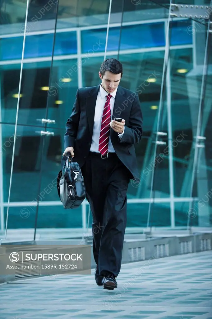 Caucasian businessman text messaging on cell phone outdoors