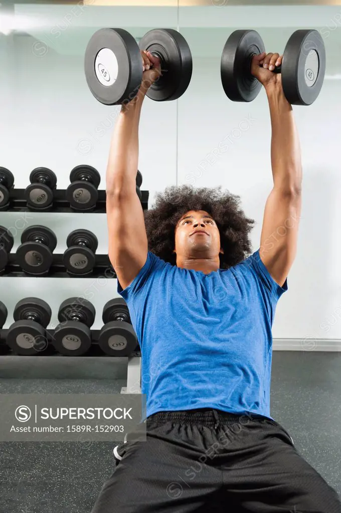 Black man lifting dumbbells in gym
