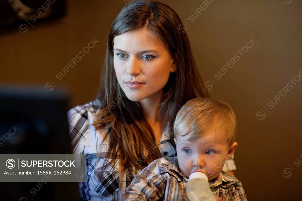 Caucasian mother using computer with son on lap