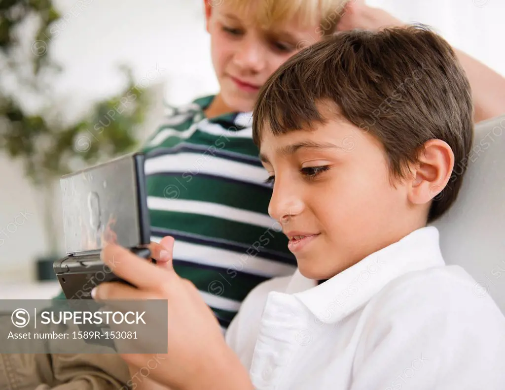 Boy watching friend playing hand_held video game