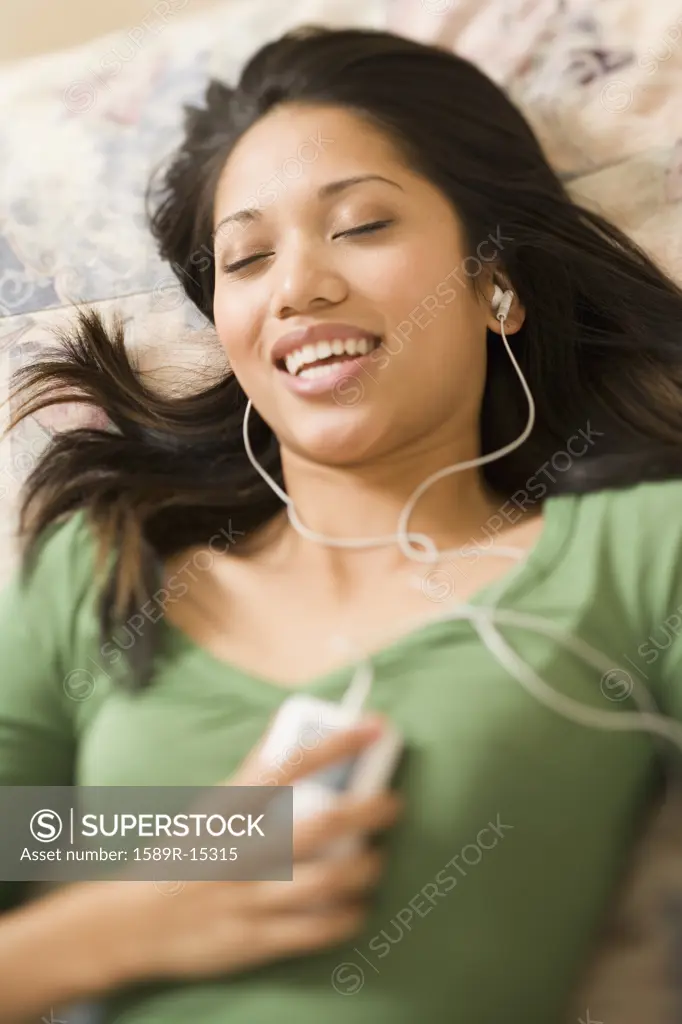 Woman laying on bed listening to music