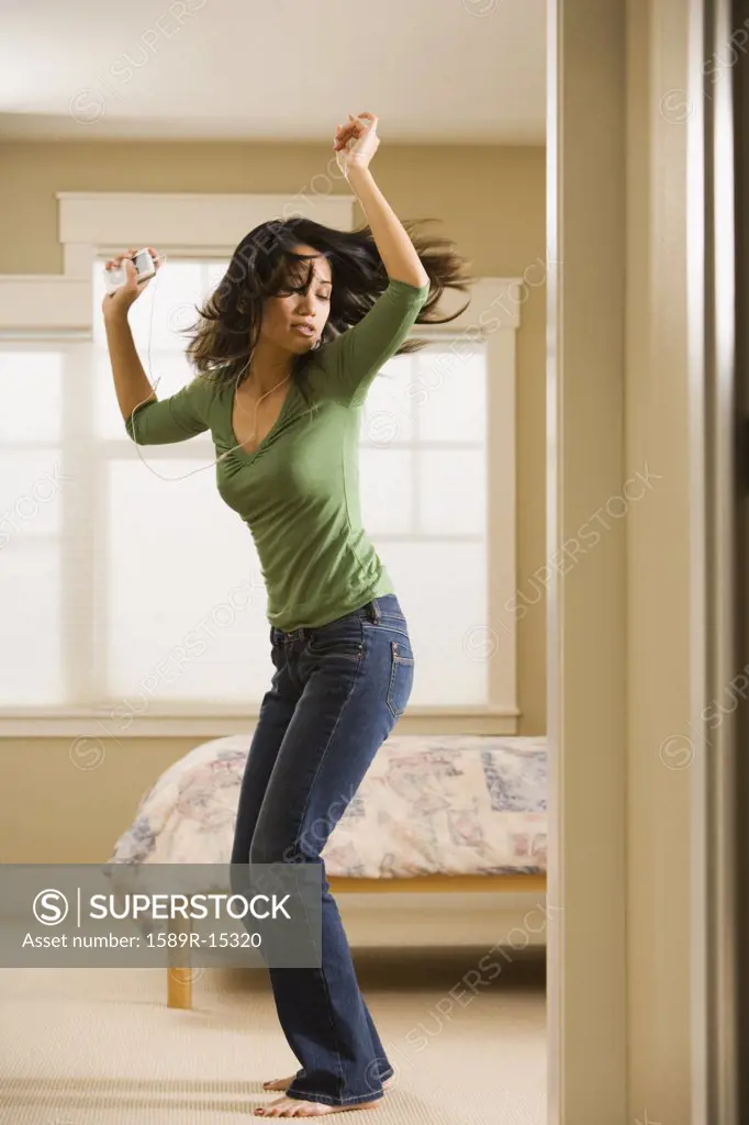 Woman dancing in bedroom while listening to music
