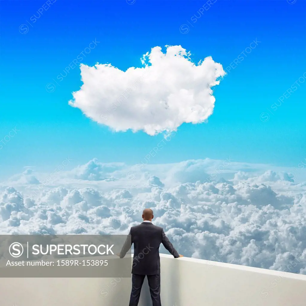Black businessman on balcony looking at clouds