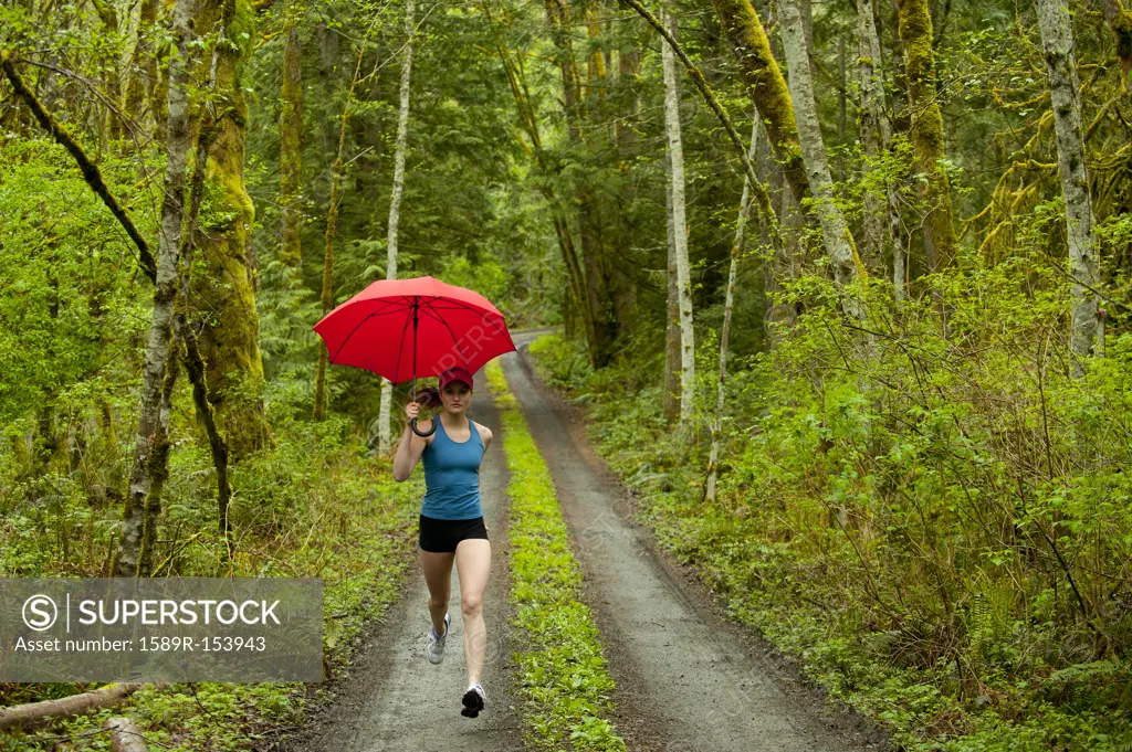 Mixed race runner training on remote road with umbrella