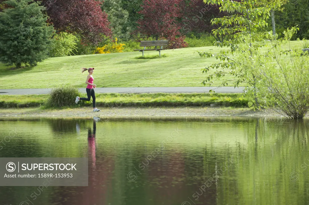 Jogger running near park pond