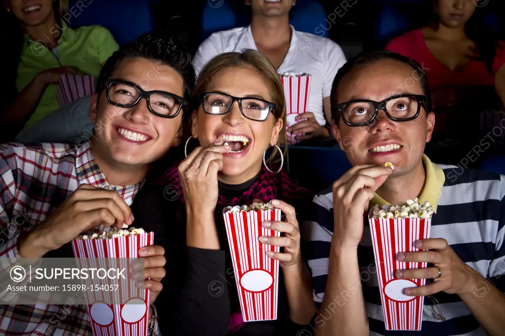 Hispanic friends enjoying popcorn at movie theater
