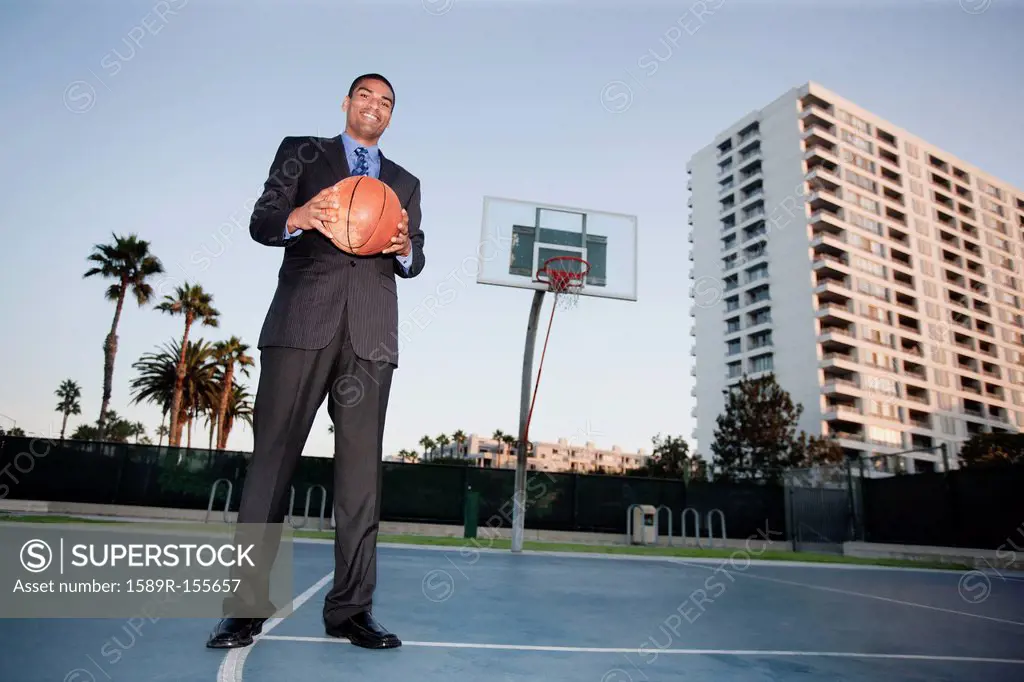 Businessman holding basketball on basketball court