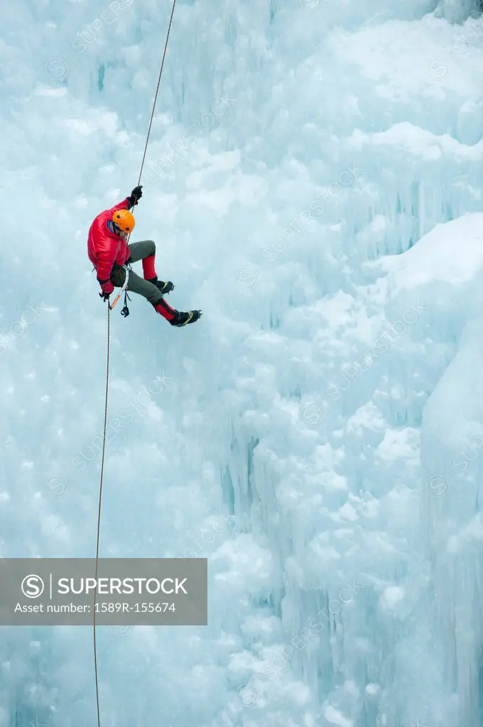 Caucasian man rappelling down ice wall