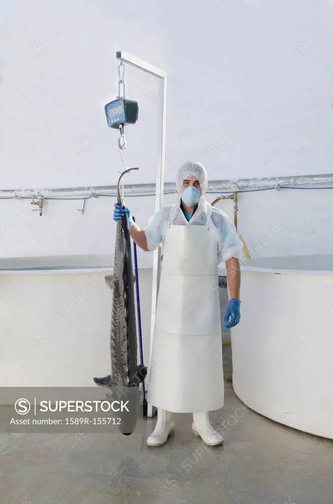 Hispanic man holding sturgeon in factory