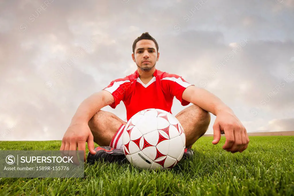 Hispanic soccer player sitting with ball