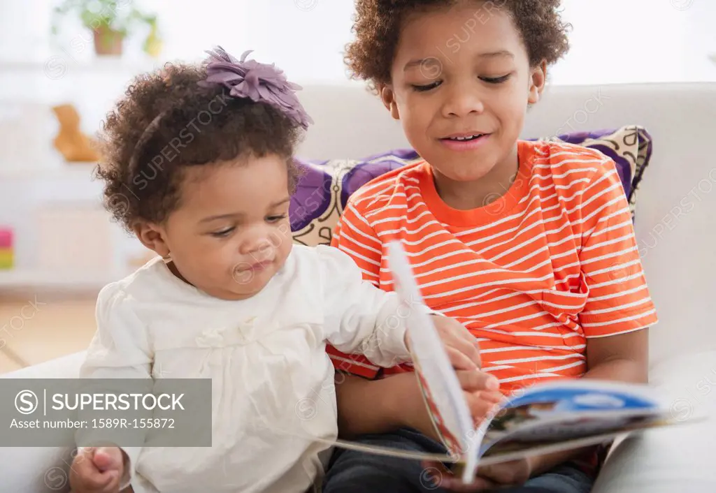Black brother reading book to sister