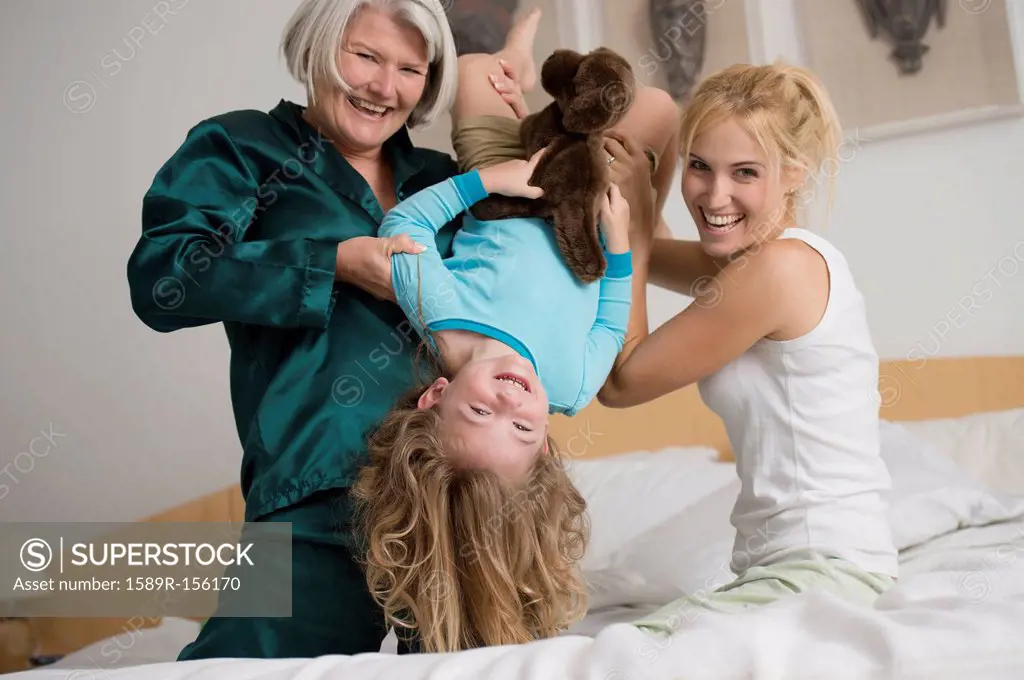 Caucasian grandmother, mother and daughter playing on bed