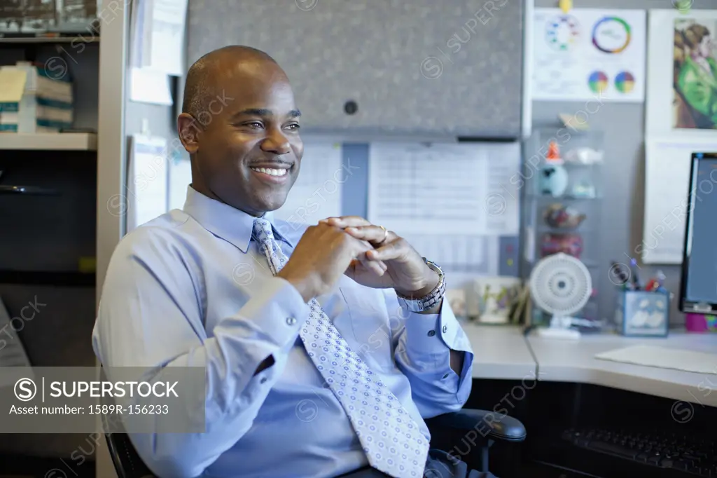 African American businessman sitting in office cubicle