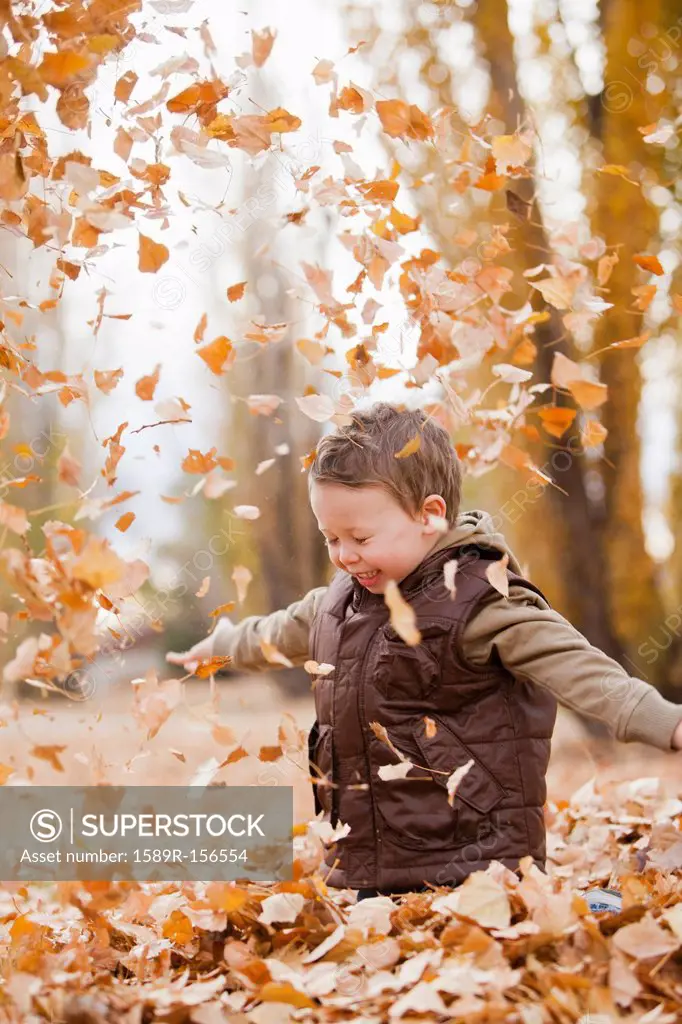 Caucasian boy playing in autumn leaves