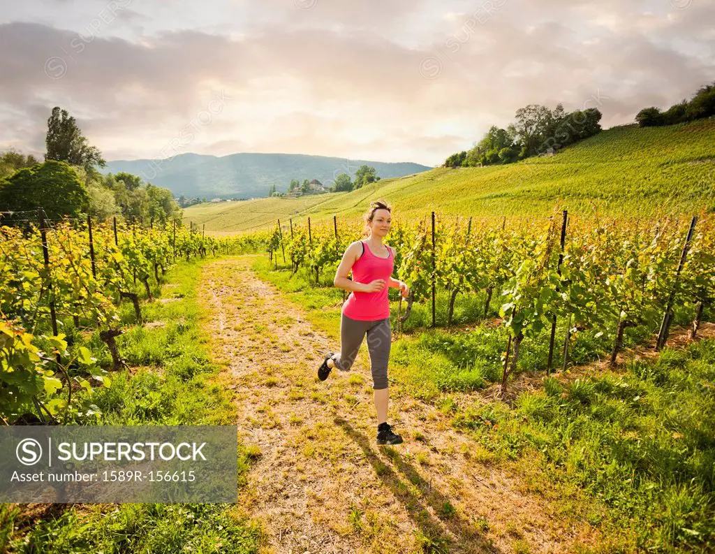Caucasian woman running in vineyard