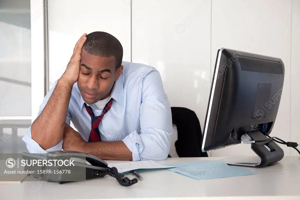 Tired Black businessman sitting at desk