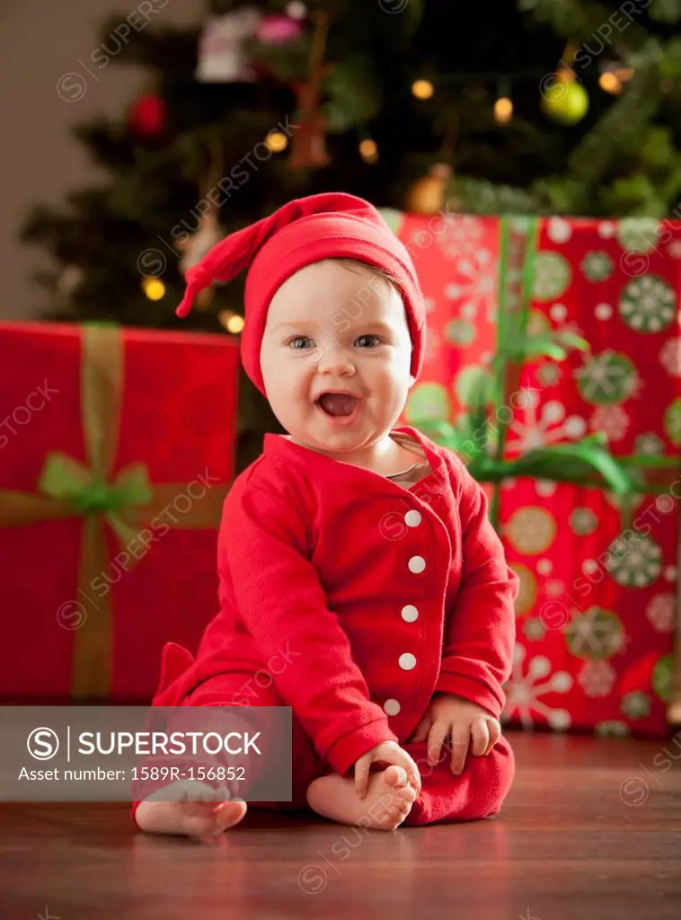 Caucasian baby boy sitting near Christmas tree