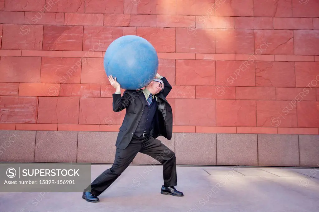 Caucasian businessman carrying heavy ball