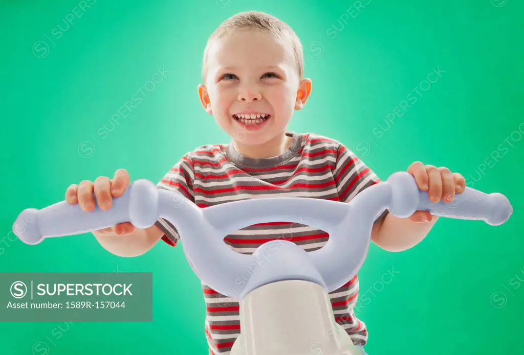 Caucasian boy riding plastic bicycle
