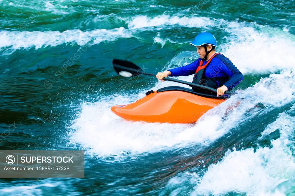 Caucasian boy kayaking on river