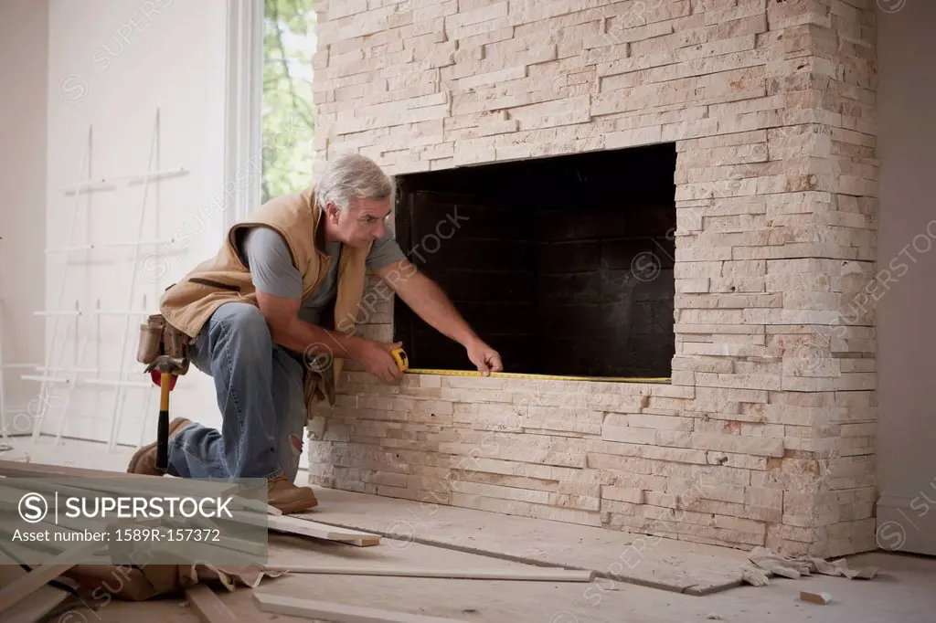 Caucasian carpenter measuring fireplace