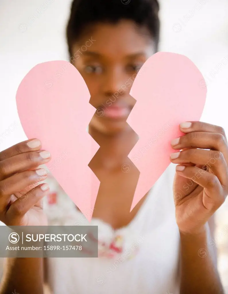 Black woman holding broken paper heart