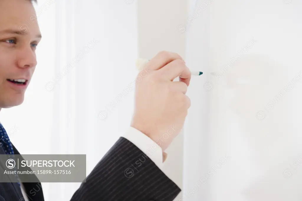 Caucasian businessman writing on whiteboard