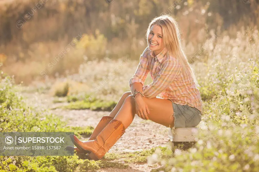 Caucasian woman sitting on tackle box in field